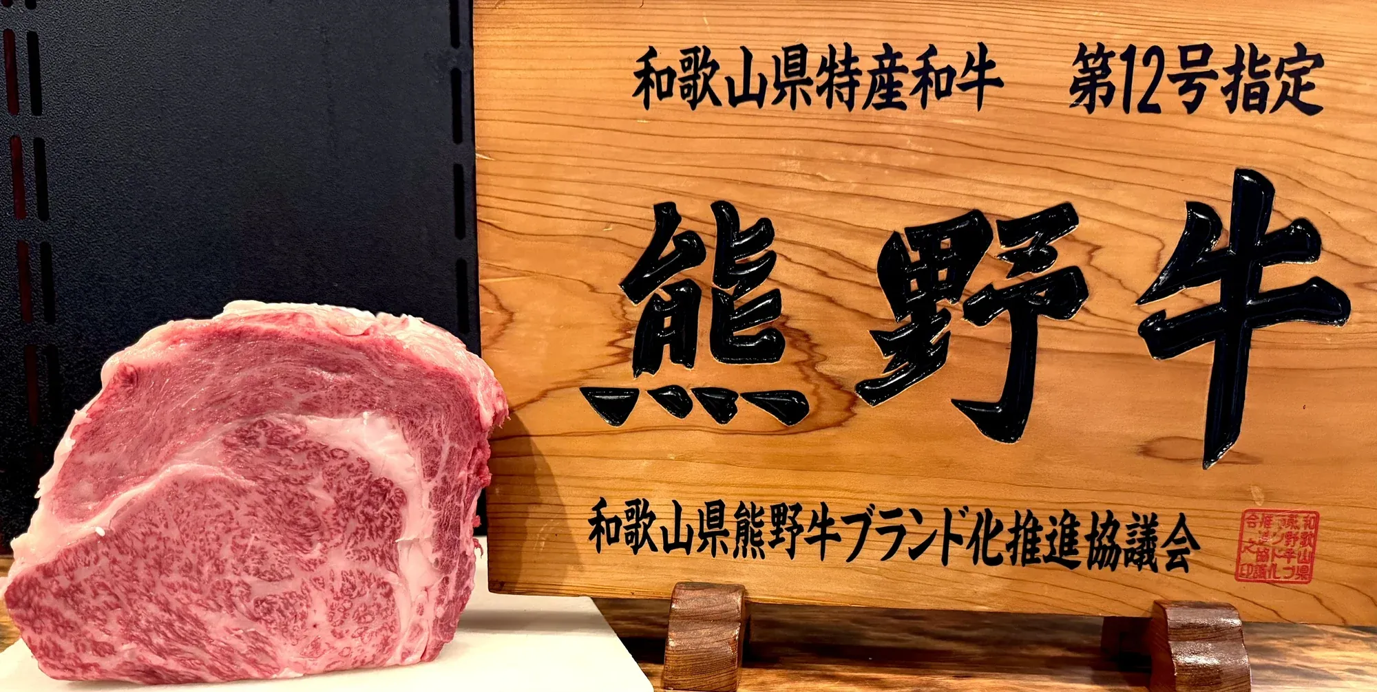 The official &ldquo;Kumano Beef&rdquo; designation sign, with a block of marbled Kumano beef