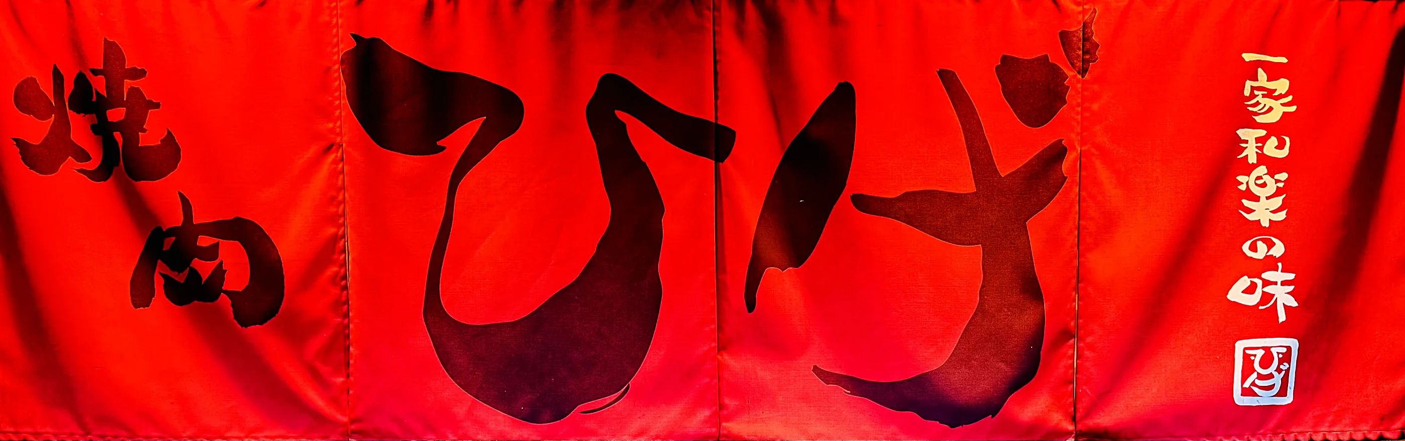A red noren curtain reading &ldquo;Yakiniku Hige&rdquo;