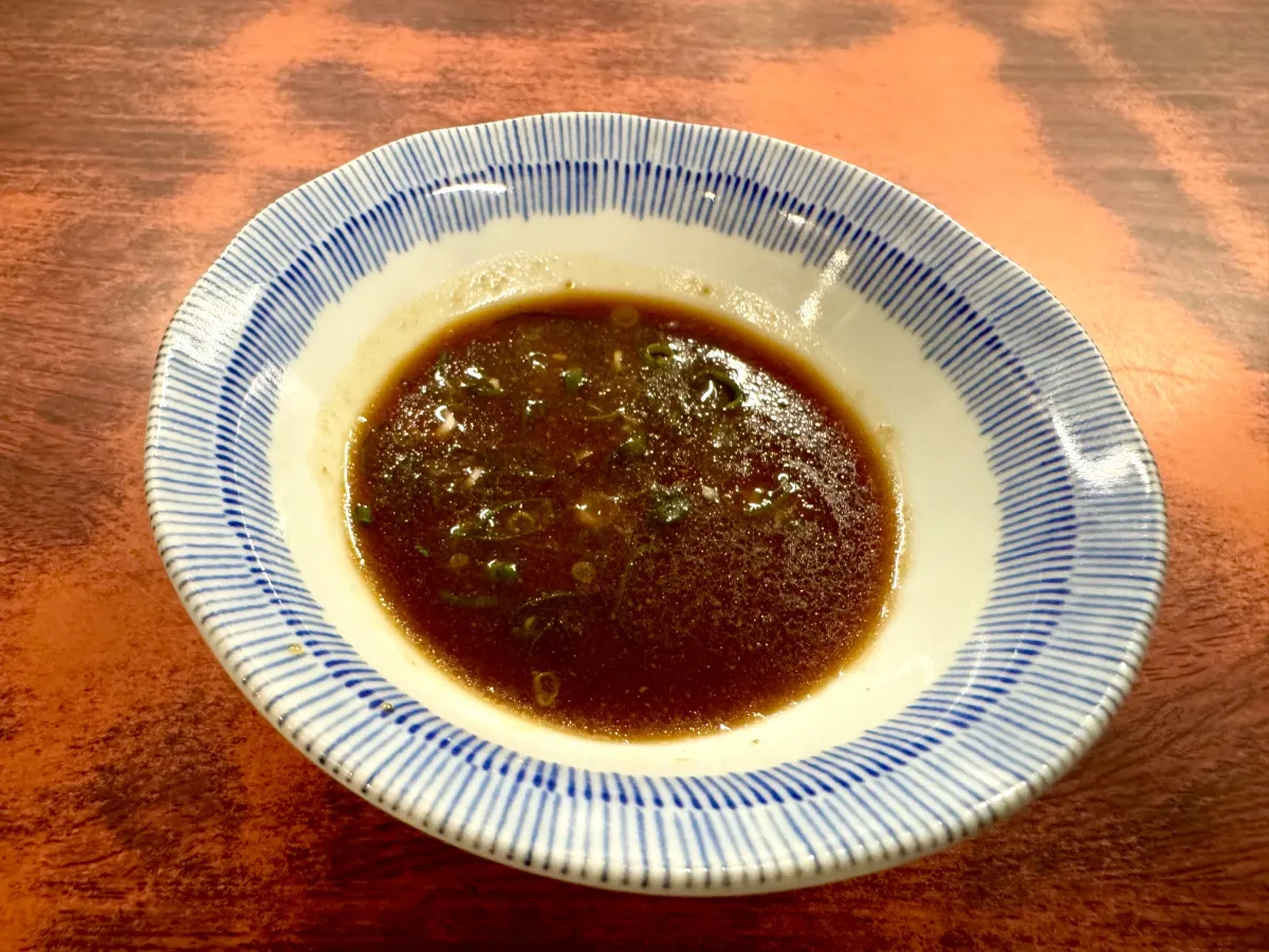 Our original secret sauce with chopped green onion, in a small blue-striped dish