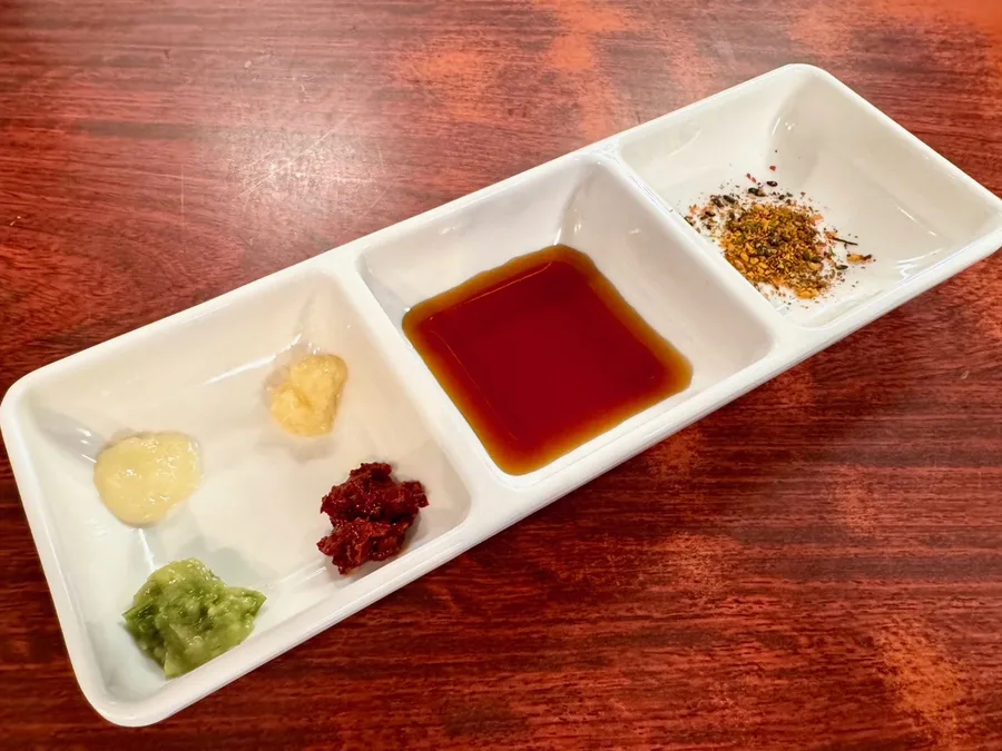 Condiments and dashi soy sauce in a divided white dish